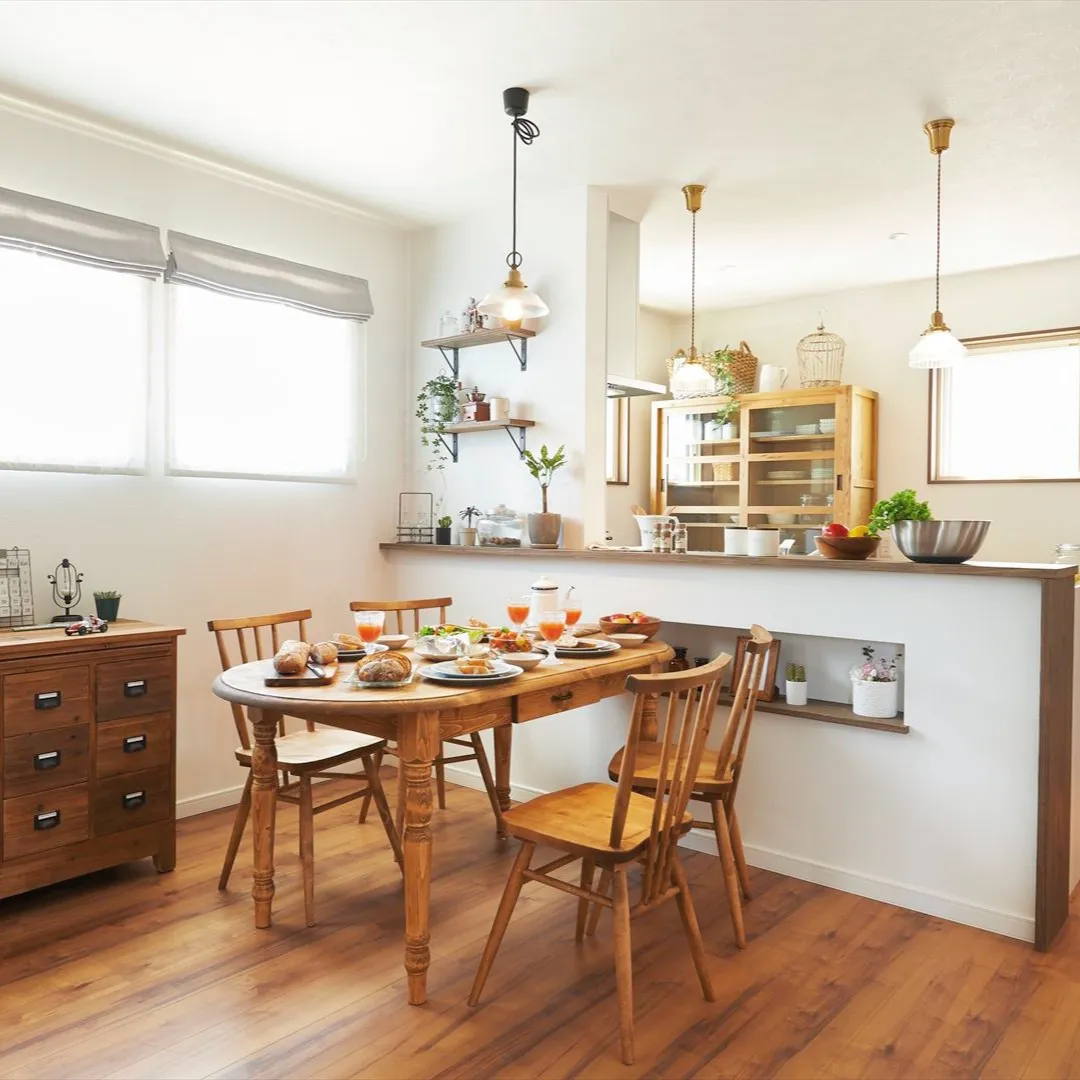 白い壁と暖かな木目調の床がマッチしたおしゃれな対面キッチン、...