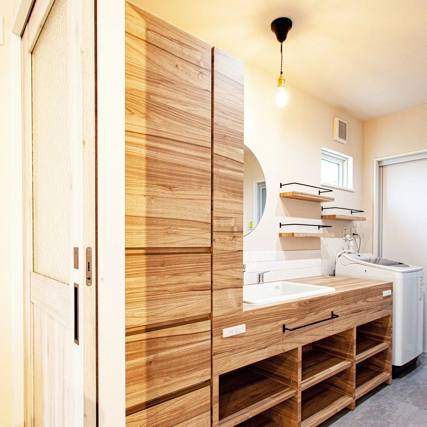 この洗面所、木製の作り付け棚が優しい雰囲気を演出して、自然の...