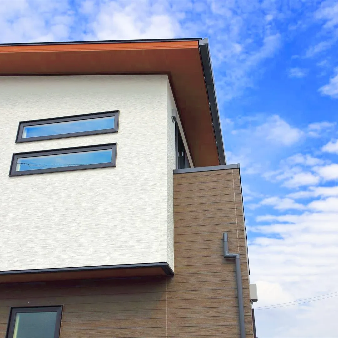 青空に映えるクリーム色とベージュのツートンカラーの家は、まさ...